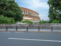 a view of a stadium from the street, showing many trees and bushes in the distance