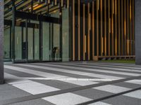 a walkway leading up to a wooden wall next to a cement area with floor tiles