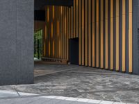 a walkway leading up to a wooden wall next to a cement area with floor tiles