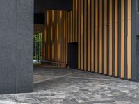 a walkway leading up to a wooden wall next to a cement area with floor tiles