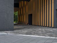 a walkway leading up to a wooden wall next to a cement area with floor tiles