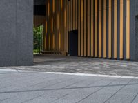 a walkway leading up to a wooden wall next to a cement area with floor tiles