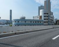 the highway is empty as it runs into the city's skyline area with a building on the other side