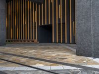 a walkway leading up to a wooden wall next to a cement area with floor tiles