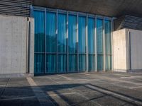 a sidewalk that has several glass doors next to it with buildings in the background behind