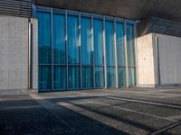 a sidewalk that has several glass doors next to it with buildings in the background behind