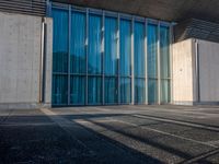 a sidewalk that has several glass doors next to it with buildings in the background behind