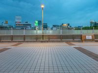 people standing on a subway platform with many buildings in the background at night light in tokyo