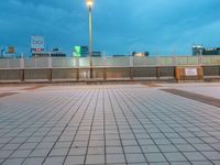 people standing on a subway platform with many buildings in the background at night light in tokyo