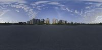 a city view in a spherical panorama from the pavement of an airport tarmac, with multiple clouds in front of the buildings and ground