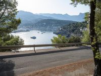 the road in the middle of the road next to the river and mountains of the sea and trees