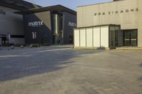 a gray building with multiple windows on each side of the street and a red sign that reads matrix