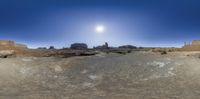 a large area with rocky terrain and blue sky in the background with a sun shining