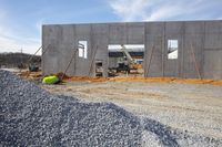 there is some concrete walls being constructed at this house under construction site and next to gravel