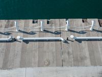 a couple of metal rails and poles near the ocean water's edge as seen from a plane