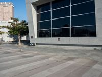 a white and grey brick building with lots of windows and a skateboarder on the sidewalk