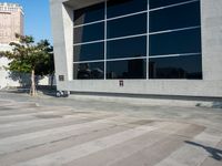 a white and grey brick building with lots of windows and a skateboarder on the sidewalk