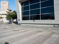 a white and grey brick building with lots of windows and a skateboarder on the sidewalk