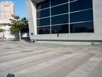 a white and grey brick building with lots of windows and a skateboarder on the sidewalk