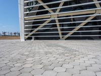 a building with an industrial design in the background and cobblestone pavers on it