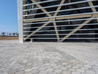 a building with an industrial design in the background and cobblestone pavers on it