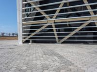 a building with an industrial design in the background and cobblestone pavers on it