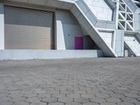 a white building has several stairs with doors on them and purple door in front of it