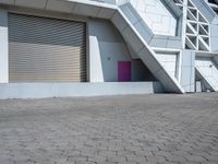 a white building has several stairs with doors on them and purple door in front of it