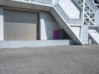 a white building has several stairs with doors on them and purple door in front of it