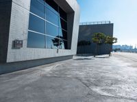 an empty parking lot with a building behind it on a sunny day with blue skies