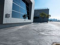 an empty parking lot with a building behind it on a sunny day with blue skies