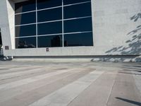 a little kid riding his bicycle on the sidewalk next to a building with a glass window