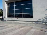 a little kid riding his bicycle on the sidewalk next to a building with a glass window