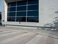 a little kid riding his bicycle on the sidewalk next to a building with a glass window