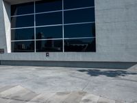 the man is walking down the side walk with his skateboard on his foot in front of a large building