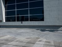 the man is walking down the side walk with his skateboard on his foot in front of a large building