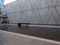 a bench that is standing in front of a concrete building with glass windows on either side