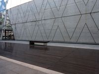 a bench that is standing in front of a concrete building with glass windows on either side