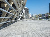 a cobble stone walk way in front of a modern, concrete building with a blue sky