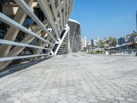 a cobble stone walk way in front of a modern, concrete building with a blue sky