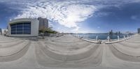 fisheye lens photo of waterfront park with building and body of water in foreground