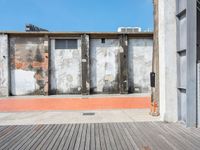 a red fire hydrant sits on a wooden deck in front of a building with an old wall