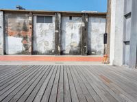 a red fire hydrant sits on a wooden deck in front of a building with an old wall