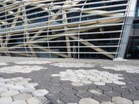 a building with many metal squares on the ground and a walkway between them and a person walking in front of the building