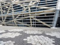 a building with many metal squares on the ground and a walkway between them and a person walking in front of the building