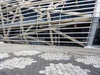 a building with many metal squares on the ground and a walkway between them and a person walking in front of the building