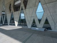 people walking through the courtyard of an architectural building with large windows and curved walls and a concrete floor