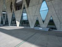 people walking through the courtyard of an architectural building with large windows and curved walls and a concrete floor