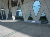 people walking through the courtyard of an architectural building with large windows and curved walls and a concrete floor