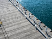 a pier with steps and railings leading into the water with bright blue waters in the background